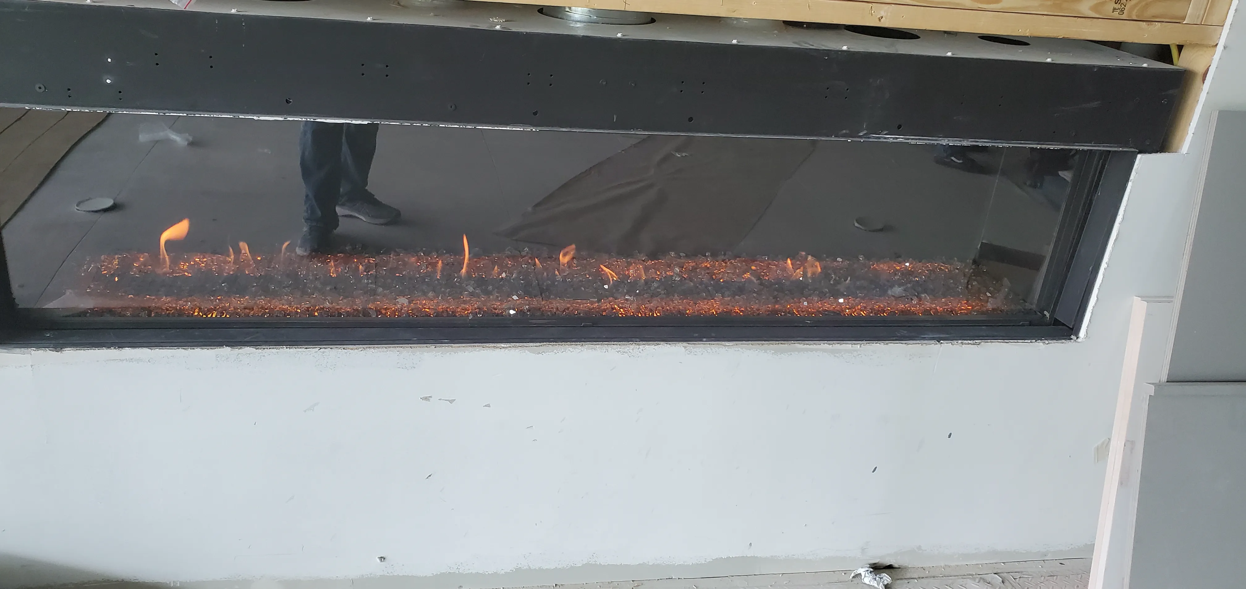Close-up of a linear gas burner with live fire in a see-through fireplace, Lou's own home in Houston